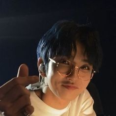 a man with glasses giving the thumbs up sign while sitting in a car at night