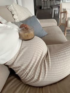 a person laying on a couch with their legs wrapped in a blanket and some food