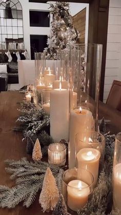 a table topped with lots of candles next to christmas trees and pine cones on top of it