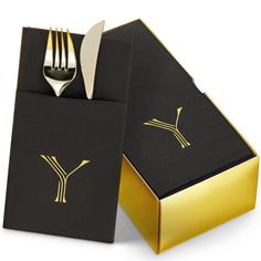 a fork and knife in a black box with gold foil on the inside that says y