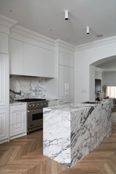 a large kitchen with marble counter tops and white cabinets, along with hardwood flooring