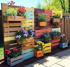 several wooden pallets with flowers in them on the side of a road near a fence