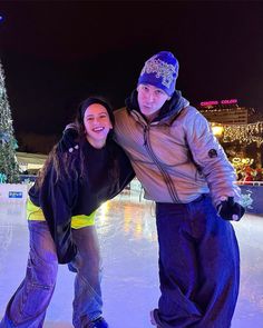 a man and woman are standing on ice skates in front of a christmas tree