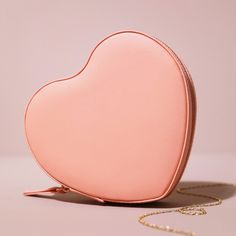 a pink heart shaped purse sitting on top of a table