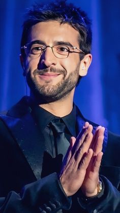 a man in a suit and tie with his hands together