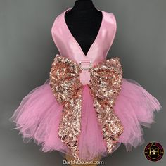 a pink and gold tutule dress with large bow on the front, attached to a mannequin head