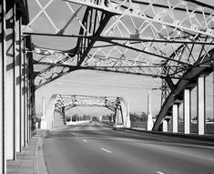 an empty street under a bridge in black and white