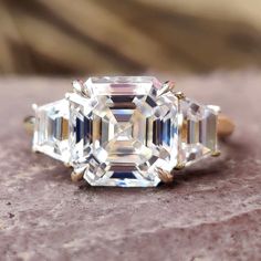 three stone diamond ring sitting on top of a rock