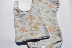 two bibs are laying next to each other on a white surface with an orange and gray pattern