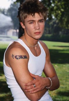 a young man with a tattoo on his arm and chest is posing for the camera