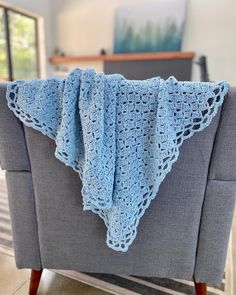 a blue crocheted blanket sitting on top of a gray chair