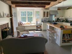 a living room filled with furniture and a fire place in front of a kitchen counter