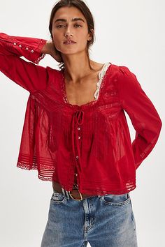 a woman is wearing a red blouse and jeans