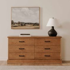 a wooden dresser sitting next to a lamp on top of a hard wood floor