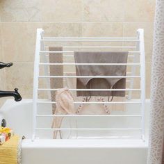 a bath tub with towels hanging on the side and a towel rack in front of it