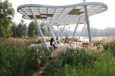 people are walking around in the grass under a canopy