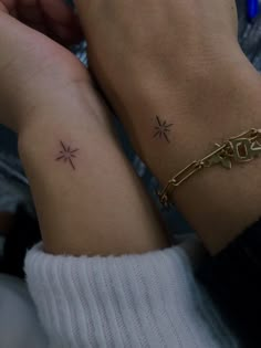 two people with matching tattoos on their arms, one is holding the other's hand