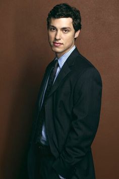 a young man in a suit and tie posing for a photo against a brown background