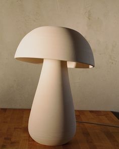 a white mushroom lamp sitting on top of a wooden table in front of a wall