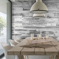 a dining room table with white chairs and a large wooden wall in the back ground