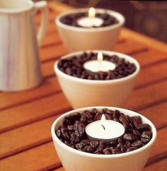 three coffee cups with candles in them sitting on a table