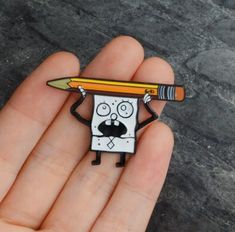 a hand holding a small cartoon character with a pencil in it's mouth and eyes