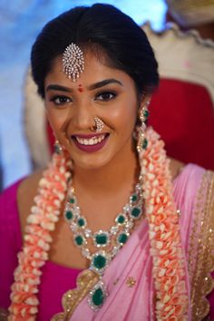 a woman in a pink sari smiles at the camera with her nose ring on