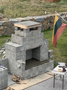 an outdoor oven made out of cinder blocks with a flag hanging from the side of it