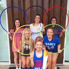 a group of young women standing next to each other in front of a door holding hoop rings