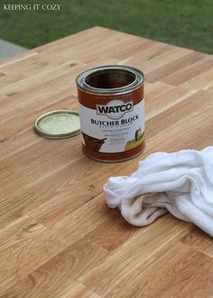 a can of paint sitting on top of a wooden table next to a white towel