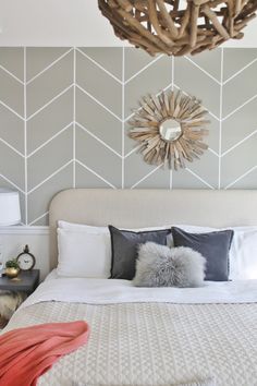 a bed with white sheets and pillows next to a wall with geometric designs on it