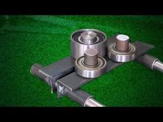 two metal rollers are on top of a green surface with grass in the background