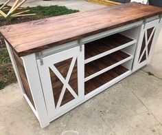 an entertainment center made out of wood and metal with sliding doors on the sides, sitting in front of a garage