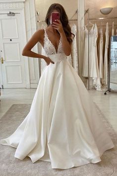 a woman taking a selfie while wearing a wedding dress in front of a mirror