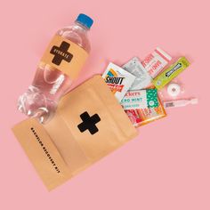 a bottle of water and some medical supplies on a pink background with a brown paper bag