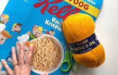 a person's hand next to a bowl of cereal and a crochet hook