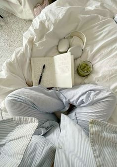 an open book and headphones on top of a bed