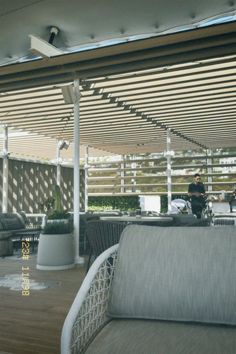 a man sitting on top of a white couch under a covered patio next to a table