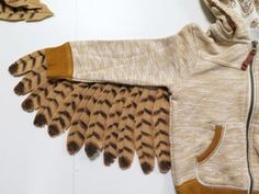 an owl's wing is attached to the hood of a sweater, which sits on top of a pair of gloves