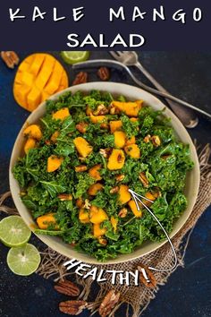 kale mango salad in a bowl with limes and nuts