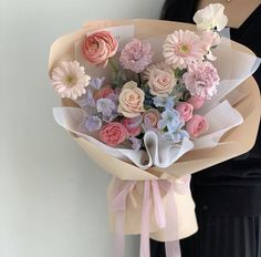 a woman holding a bouquet of pink and white flowers in her hands with a black dress