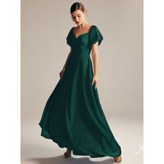 a woman in a long green dress is looking down at the camera and she has her hand on her hip