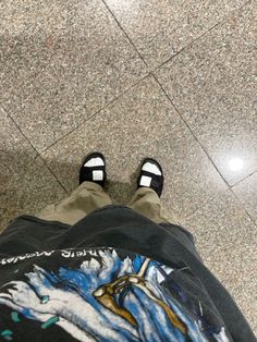 a person with black and white shoes standing in front of a tile floor