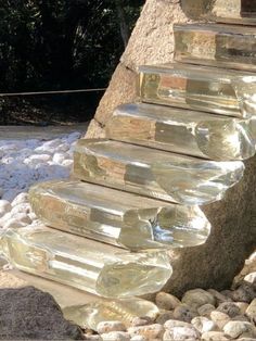 several glass bottles are stacked on top of each other in front of a rock wall