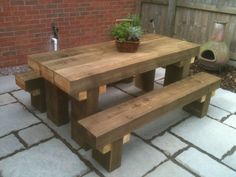 a wooden table with two benches and a potted plant