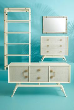 a white dresser sitting next to a mirror on top of a blue wall