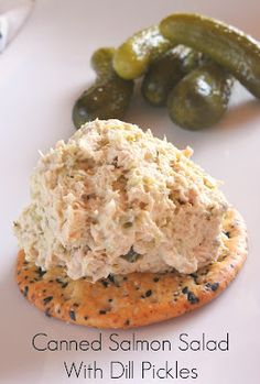 a close up of a sandwich on a plate with pickles in the background and text that reads canned salmon salad with dill pickles