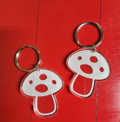 two red and white keychains on a red surface with a dog's head