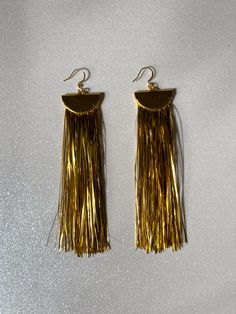 Gift yourself or a friend a unique set of gold metallic tinsel tassel earrings for a special occasion. They feature 18K gold and a tinsel fringe that dangle perfectly from your ears for a festive look. Upgrade any outfit for a holiday party, New Year’s Eve, or any special event! Materials: 18K gold hook, gold half moon, tinsel fringe Fringe Length: 4in Gold Tassel Jewelry For Celebration, Gold Jewelry With Tassels For Celebrations, Yellow Gold Dangle Tassel Earrings For Party, Glamorous Gold Dangle Tassel Earrings, Glamorous Gold Fringe Earrings, Gold Fringe Tassel Dangle Earrings, Gold Dangle Tassel Earrings With Fringe, Gold Dangle Tassel Earrings, Gold Elegant Tassel Earrings For Party