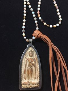 This carved stone Buddha is hand crafted by monks in Thailand who have been producing sacred amulets for over two centuries. The beads on the necklace are amonazite & jasper. The leather tassel adds a bit of flair to this piece. Adjustable Carved Spiritual Necklace, Spiritual Carved Beaded Necklace As Gift, Spiritual Carved Beaded Necklace For Gift, Carved Beaded Necklaces For Spiritual Gifts, Artisan Medallion Necklace For Meditation, Bohemian Hand-strung Jewelry For Blessings, Spiritual Bronze Hand Wrapped Necklaces, Bronze Spiritual Hand Wrapped Necklaces, Bronze Carved Spiritual Jewelry